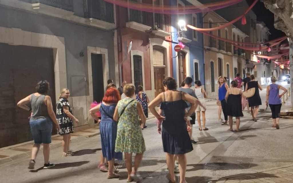 A LES PORTES DE LA FESTA, ADORNANT CARRER. ENTRE TELES I POMPONS, EL CARRER SIGNES MIRA A L'ERMITA