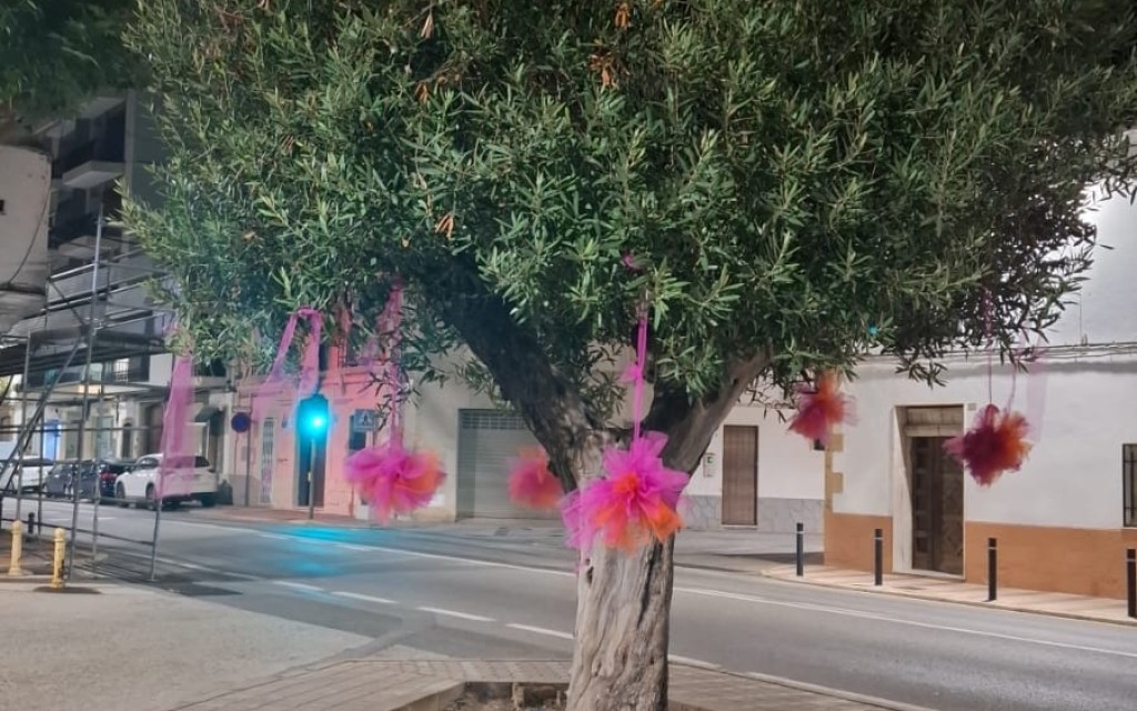 A LES PORTES DE LA FESTA, ADORNANT CARRER. ENTRE TELES I POMPONS, EL CARRER SIGNES MIRA A L'ERMITA
